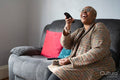 Mature woman sitting in living room and watching TV