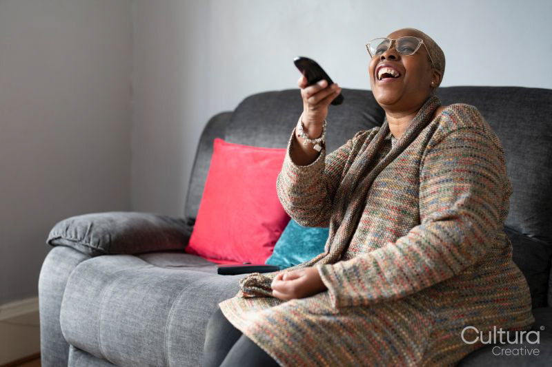 Mature woman sitting in living room and watching TV