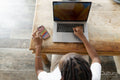 Young woman using smart phone while working on laptop at home