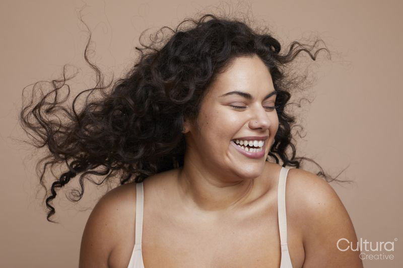 Studio shot of smiling young woman with curly hair