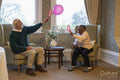 Smiling senior man and woman playing with balloon in nursing home
