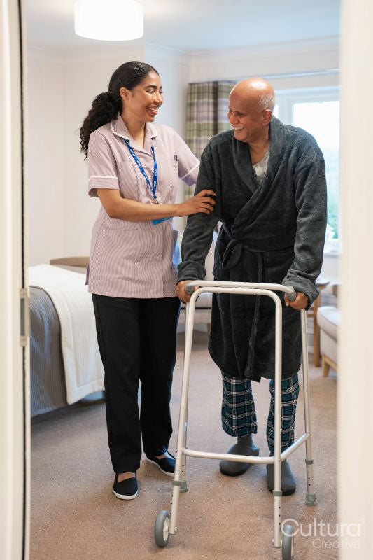 Nurse helping senior man to walk with mobility walker at nursing home