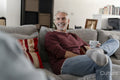 Smiling mature man relaxing on sofa at home
