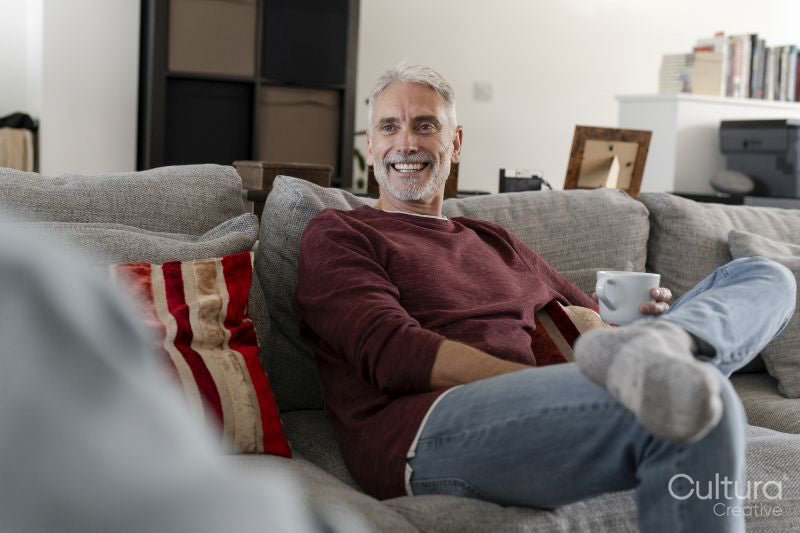 Smiling mature man relaxing on sofa at home
