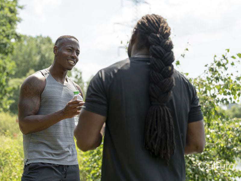 Two men drinking water after exercising outdoors
