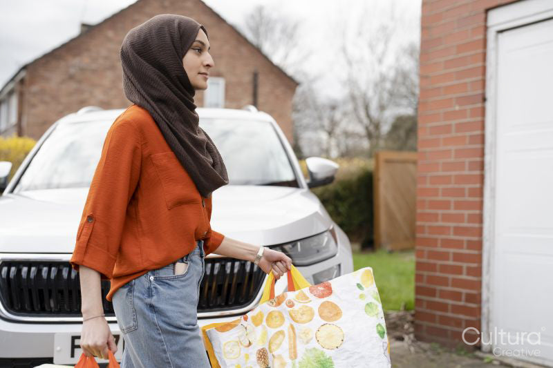 Woman wearing hijab returning home with shopping bags