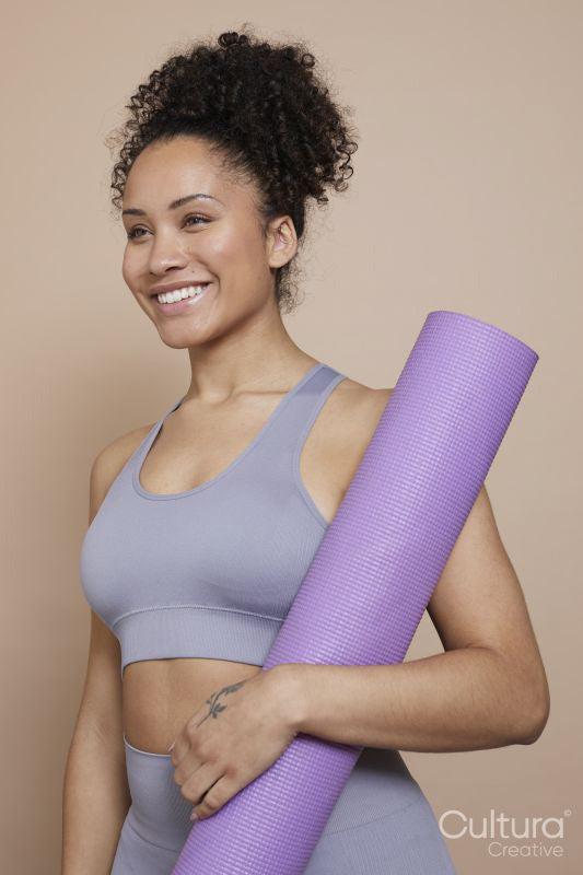 Studio portrait of smiling athletic woman with yoga mat