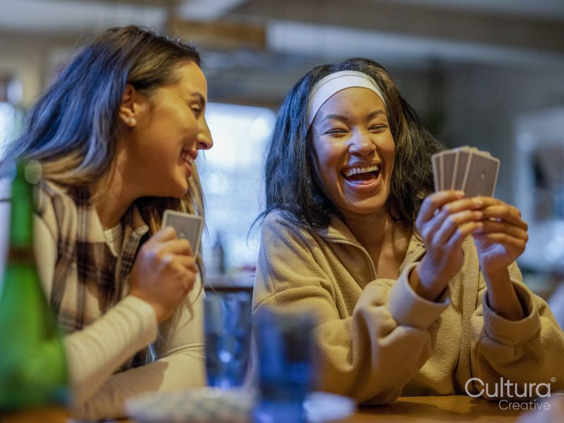 Friends laughing while playing cards at home