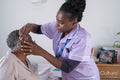 Caregiver adjusting senior woman's hearing aid