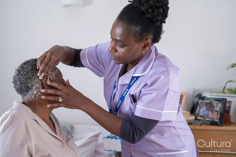 Caregiver adjusting senior woman's hearing aid
