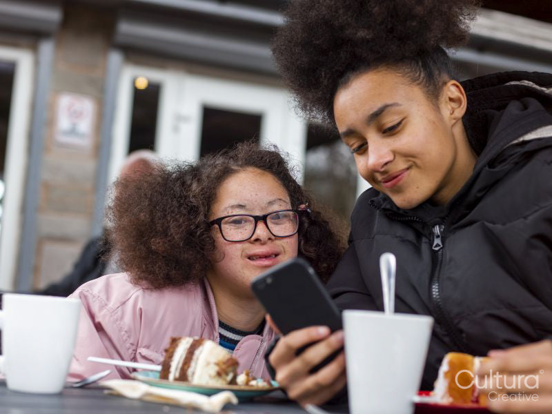 Two girls checking mobile phone in cafe