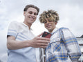 Smiling male couple using smart phone