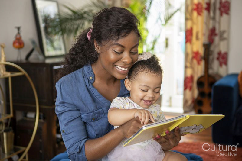 Mother reading to baby daughter at home