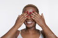 Studio portrait of smiling woman with hands covering eyes