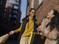 Two young women with shopping bags in urban setting