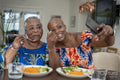 Smiling senior woman with adult daughter eating dinner and taking selfie