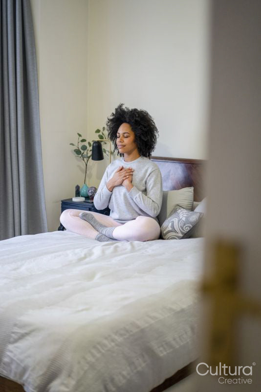 Young woman meditating on bed