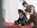 Mother wrapping traditional turban on son's head