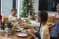 Girl with grandmother holding Christmas cracker across table