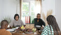 Family with children praying before Kwanzaa meal