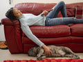 Woman watching television while stroking French Bulldog in living room