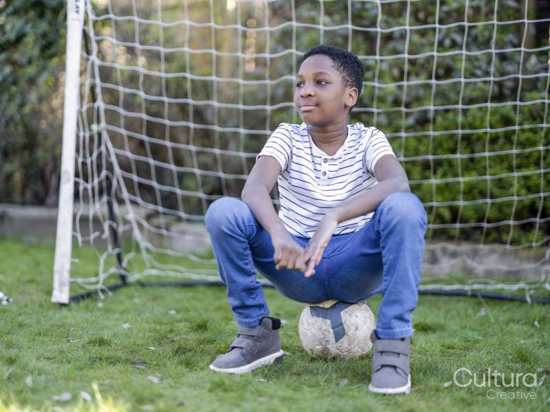 Boy sitting on football in back yard
