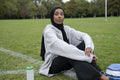 Portrait of woman in hijab sitting in soccer field