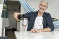 Mature man pouring red wine at home