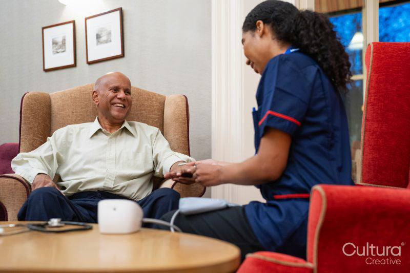 Nursing assistant using pulse oximeter on senior man at nursing home