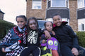 Portrait of smiling children in Halloween costumes sitting in front of house
