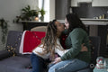 Two women sitting on sofa and kissing