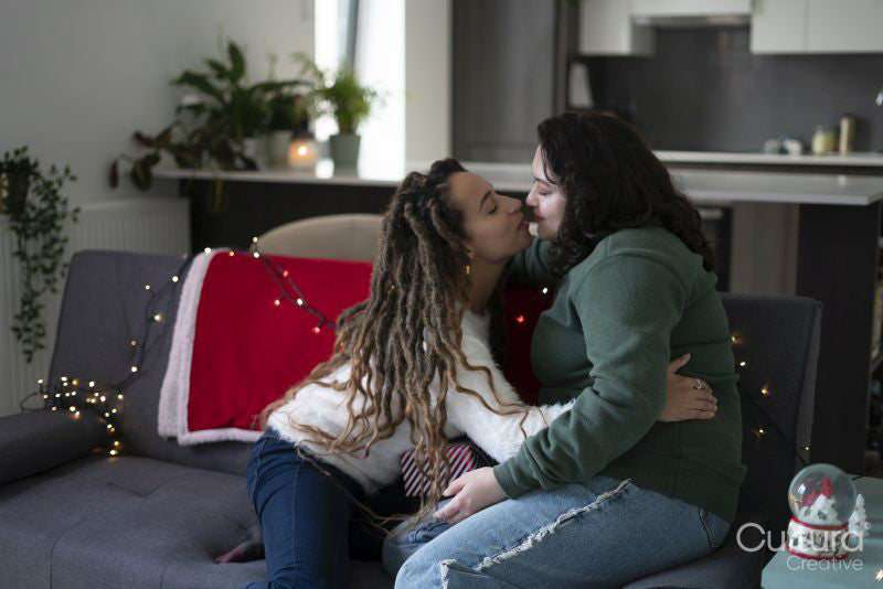 Two women sitting on sofa and kissing