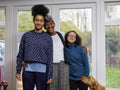 Portrait of mother embracing two daughters at home