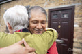 Smiling senior couple embracing in front of house