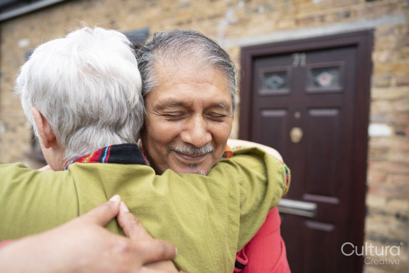 Smiling senior couple embracing in front of house