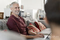 Smiling mature man working on laptop on sofa at home