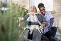 Smiling nurse and senior woman in wheelchair relaxing in park