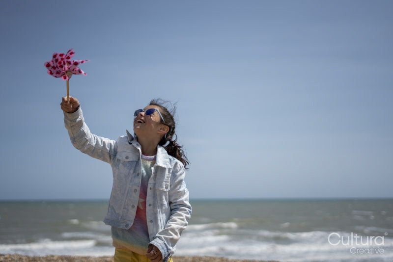 Girl playing with pinwheel on beach