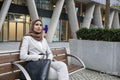 Woman in business clothing and hijab sitting on bench