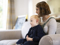 Daughter sitting on mothers lap at home