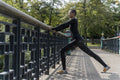 Athletic woman stretching legs on footbridge in park