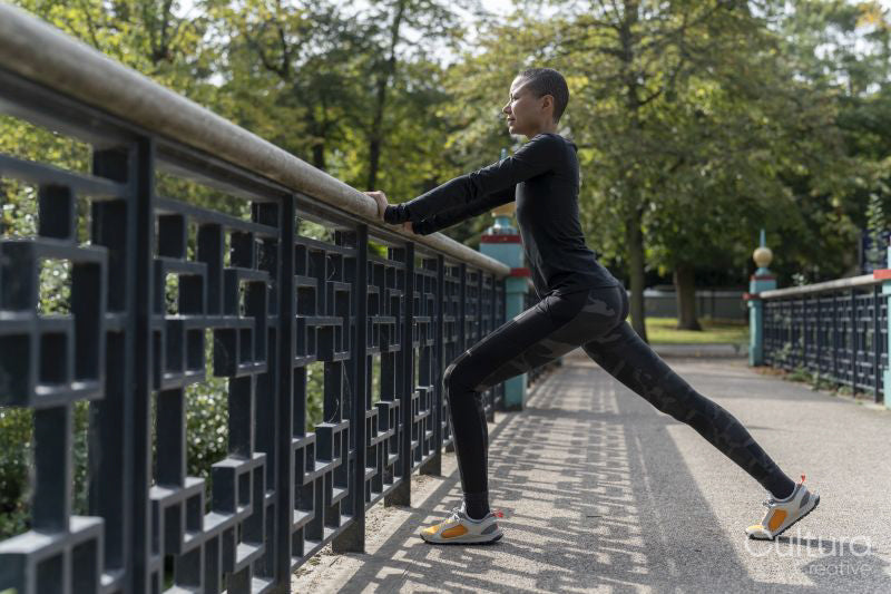 Athletic woman stretching legs on footbridge in park