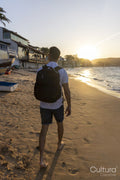 Rear view of man with backpack on beach at sunset