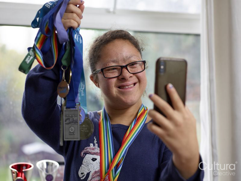 Girl with Down syndrome taking selfie with medals