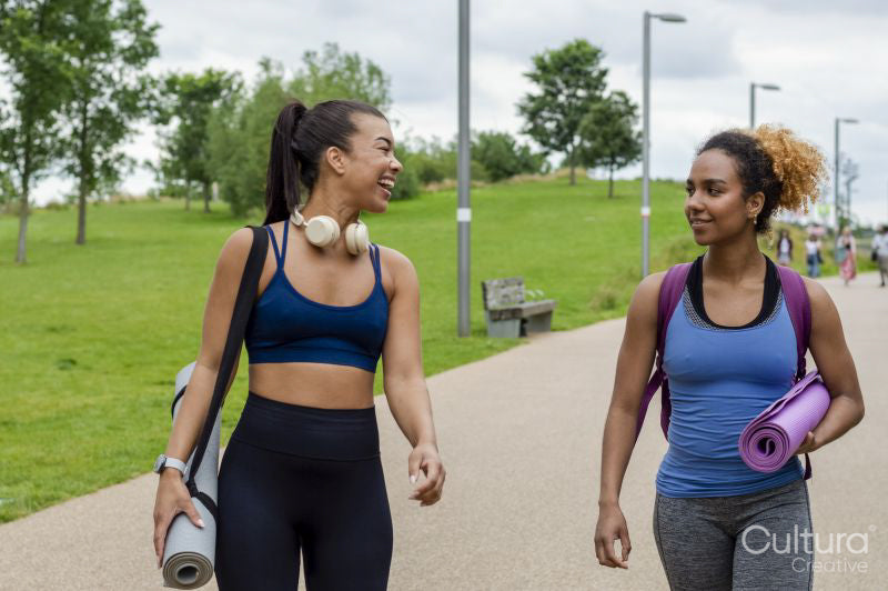 Female friends walking with yoga mats