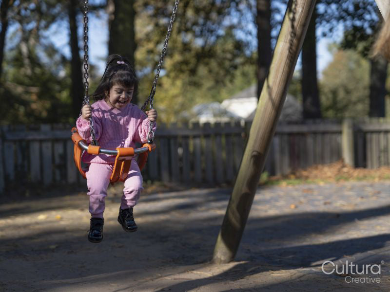 Girl with Down syndrome swinging on swing on playground