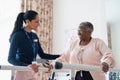 Smiling female therapist assisting senior woman walking on bars