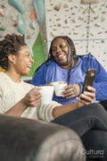 Mother and daughter laughing while using smart phone next to climbing wall