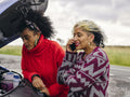 Women standing over broken car