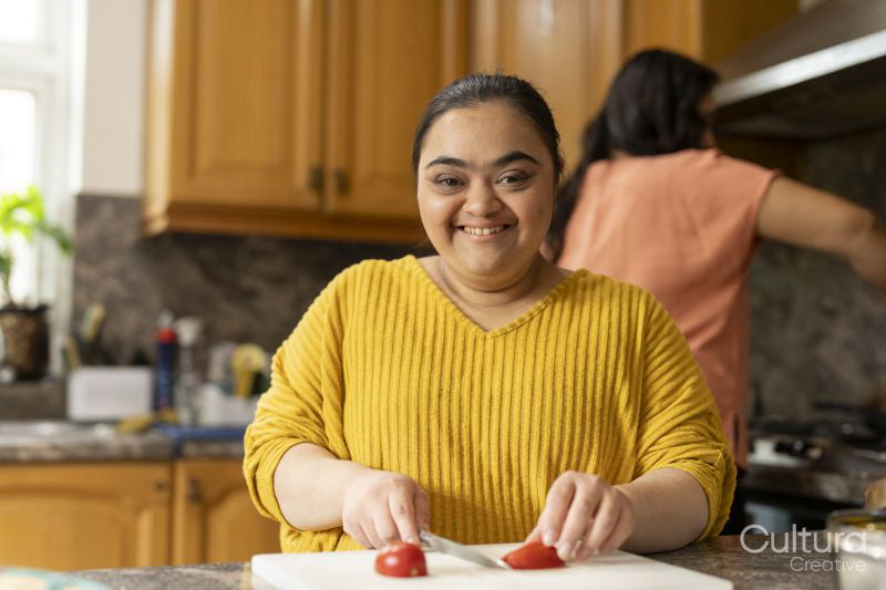 Portrait of woman with down syndrome preparing food with mother in kitchen